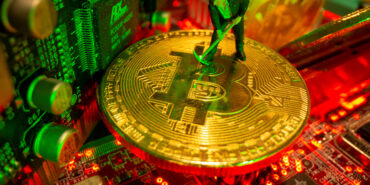 FILE PHOTO: A small toy figure and representations of the virtual currency bitcoin stand on a motherboard in this picture illustration